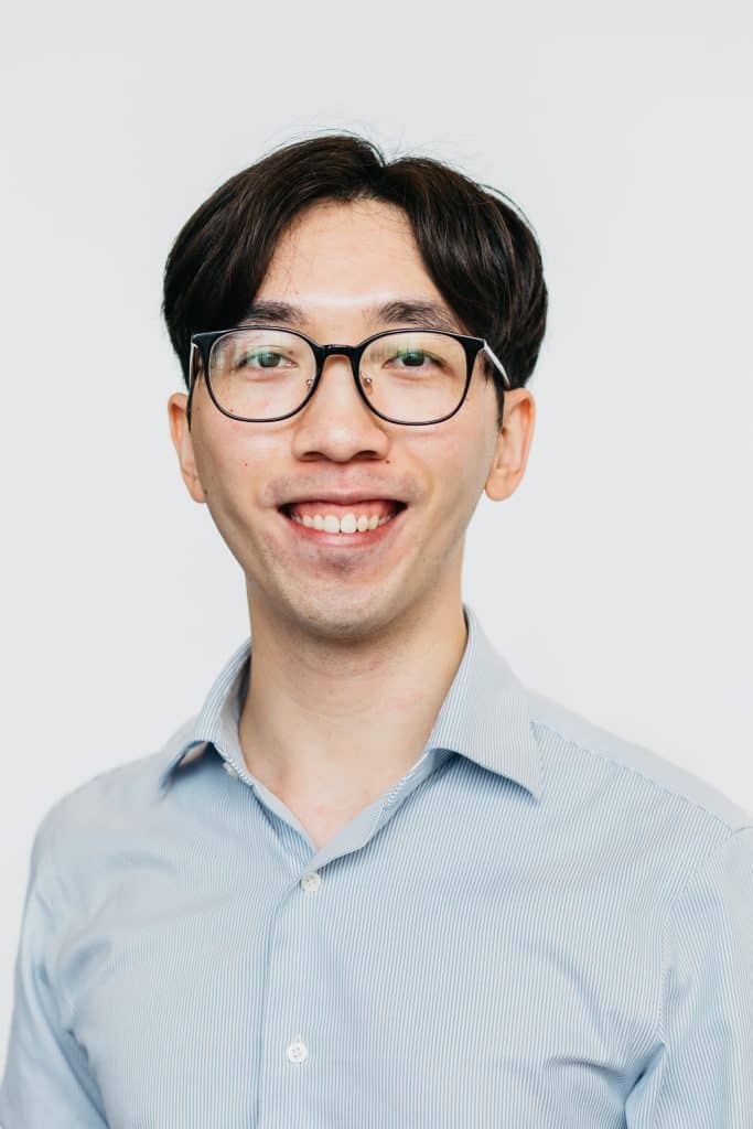 Smiling man with glasses in a light blue shirt, promoting eye health and vision care.