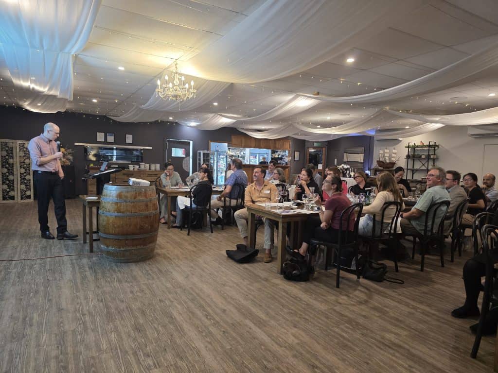 Community event with attendees listening to a speaker in a decorated venue.